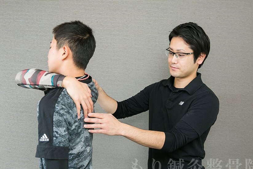 背中側から肩甲骨の位置を確認している様子