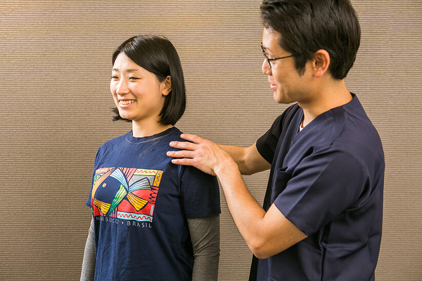 立った方の肩に手を添えて説明しているところ
