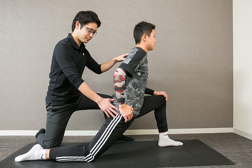 片ひざをついた姿勢で骨盤の動きを確かめる場面