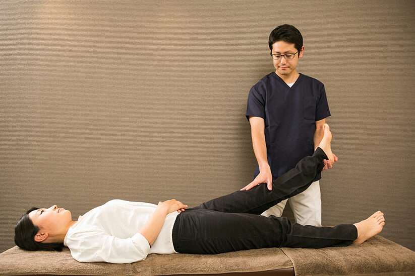 仰向けに寝た方の片脚を、膝を伸ばしたまま持ち上げているところ
