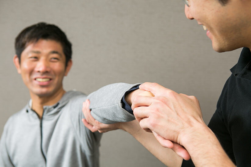 ひじを両手で支えて動きを確かめる場面