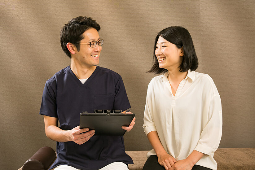 施術者がクリップボードを持ち、向かい合って話を聞いているところ