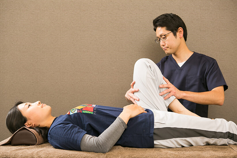 仰向けの姿勢でひざを抱えるように脚を曲げる場面