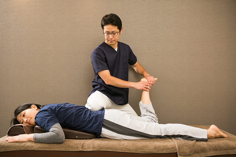 仰向けの姿勢で腰から脚にかけて施術を受ける場面