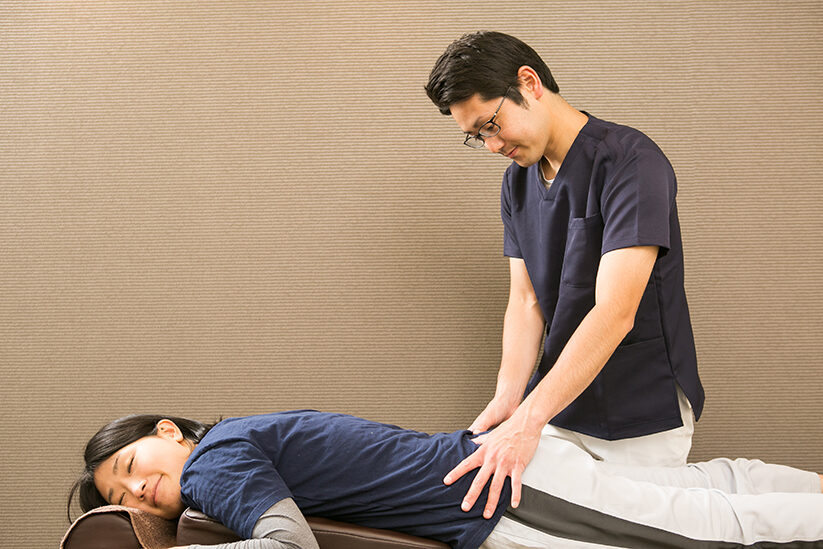 うつ伏せに寝た方の腰に両手を当てているところ